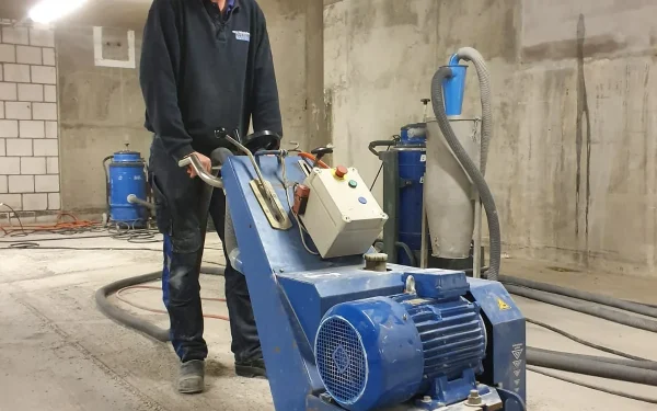 Medewerker freest betonvloer in parkeergarage met professionele vloesfreesmachine voor gelijkmaken ondergrond