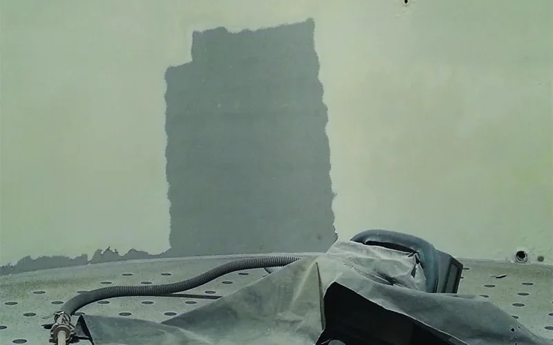 Sloopwerkzaamheden aan hoog gebouw met graafmachine en bouwmaterialen op de voorgrond