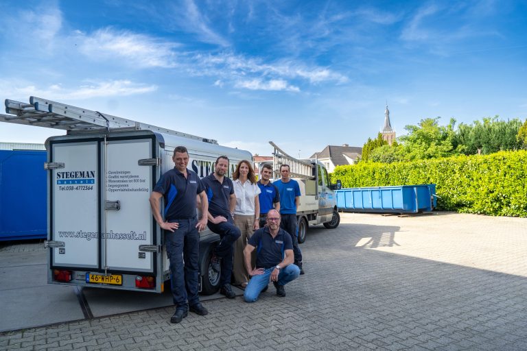Team van monteurs poseert voor servicewagens met hoogwerker bij bedrijfspand