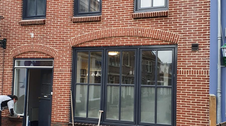 Renovatie van bakstenen gevelpand met nieuwe kozijnen en grote raampartij op de begane grond