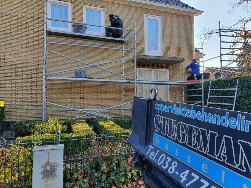 Professionele gevelreiniging met steiger bij woning met bakstenen gevel en blauwe ramen
