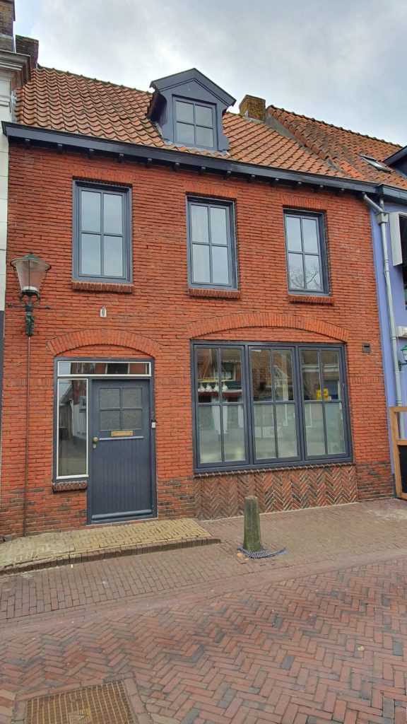 Leegstaand winkelpand met rode bakstenen gevel en grote etalageruiten in historisch stadscentrum