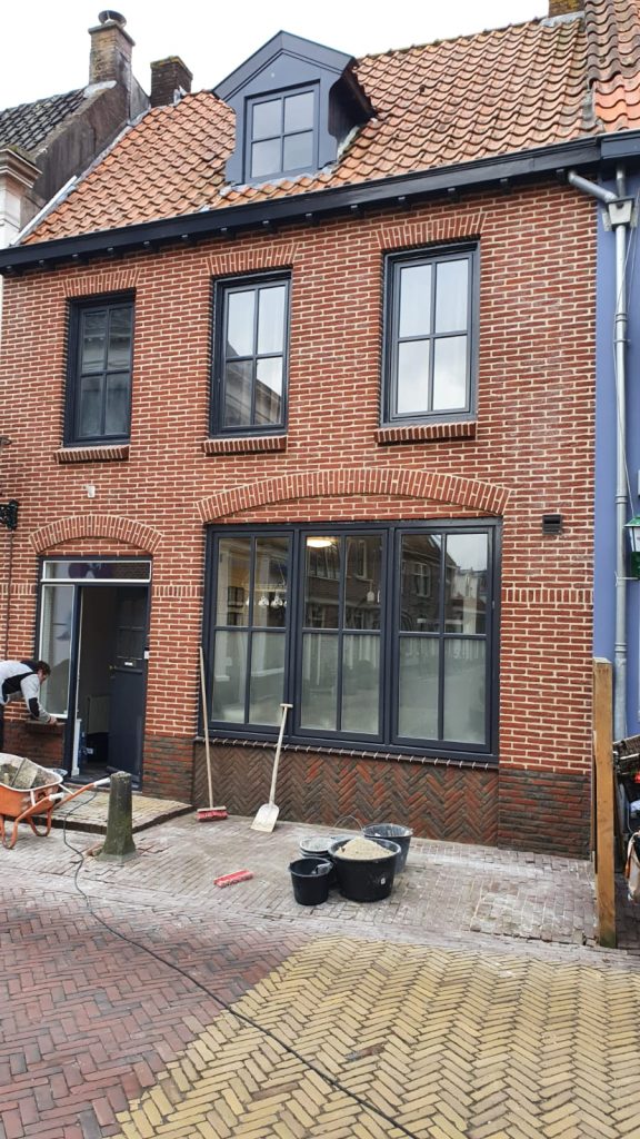 Renovatie van bakstenen gevel met nieuwe kozijnen en grote raampartij op de begane grond
