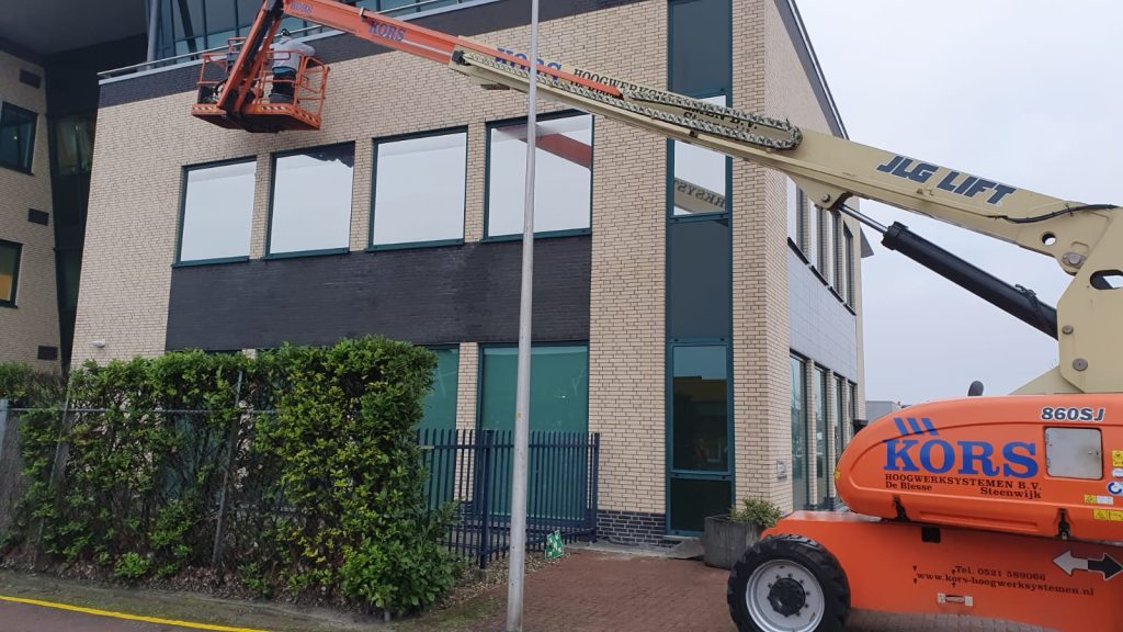 Gevelreiniging van kantoorpand met hoogwerker en hogedrukspuit door reinigingsbedrijf