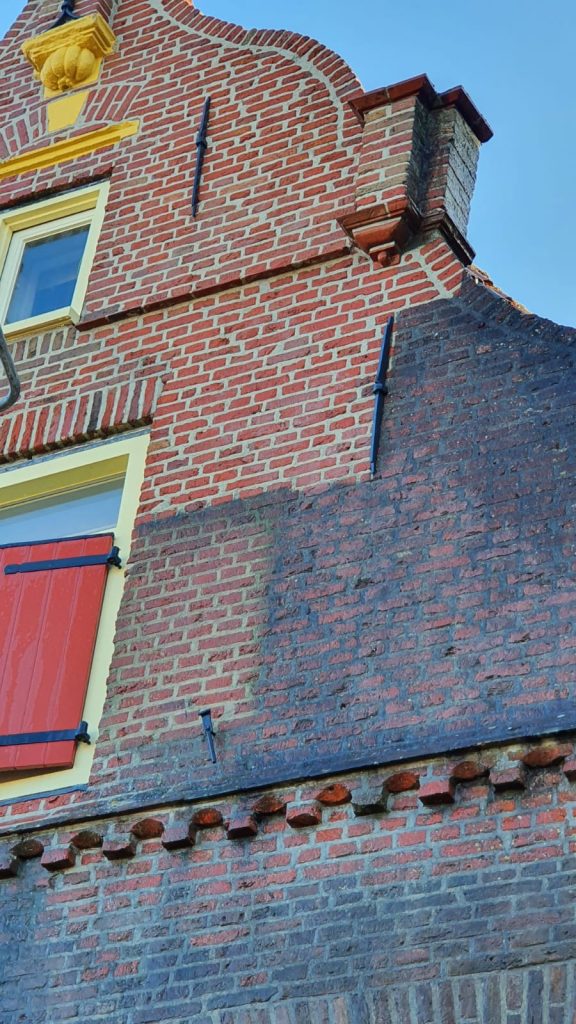 Gerenoveerde bakstenen schoorsteen met sierprofiel en hersteld metselwerk op pannendak